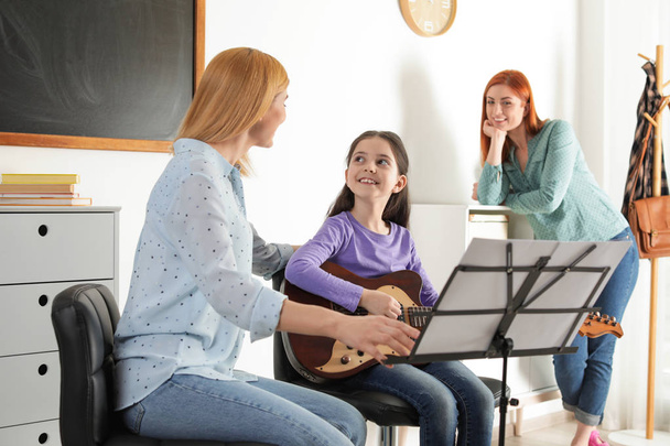 Little girl with her teacher and mother at music lesson. Learning notes - Foto, Bild