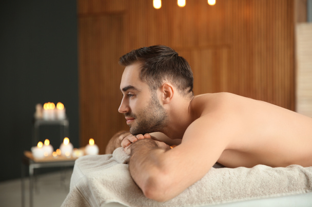 Bonito homem relaxante na mesa de massagem no salão de spa
 - Foto, Imagem