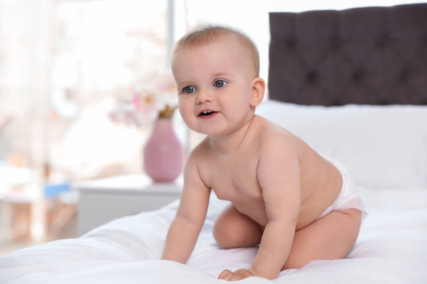 Cute baby in diaper on bed at home - Foto, imagen