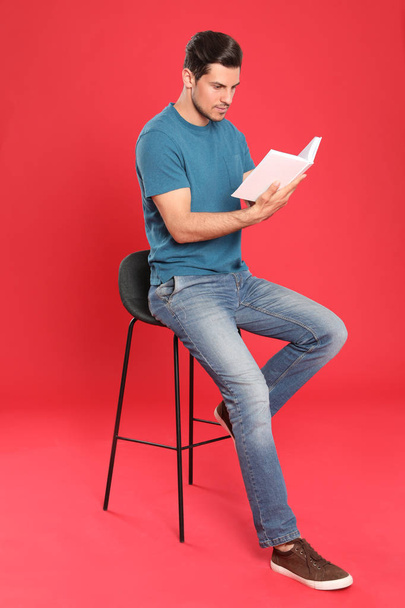 Handsome man reading book on color background - Photo, Image
