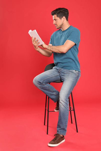 Handsome man reading book on color background - Fotoğraf, Görsel