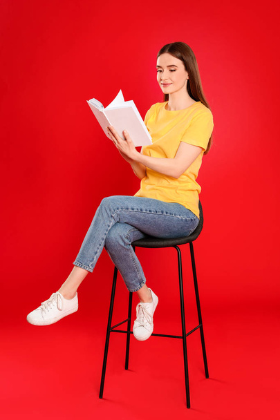 Young woman reading book on color background - Foto, afbeelding