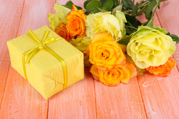 Beautiful bouquet of roses with gift on table close-up - Фото, изображение