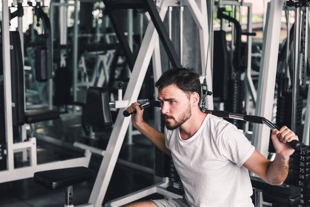 Handsome Man is Exercising with Lifting Machine in Fitness Club., Portrait of Strong Man Doing Working Out Calories Burning in Gym., Healthy and Fitness Lifestyle Concept
. - Фото, изображение