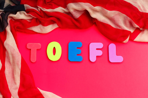 Woord TOEFL en Amerikaanse vlag op rode achtergrond. USA examen. Speaki - Foto, afbeelding