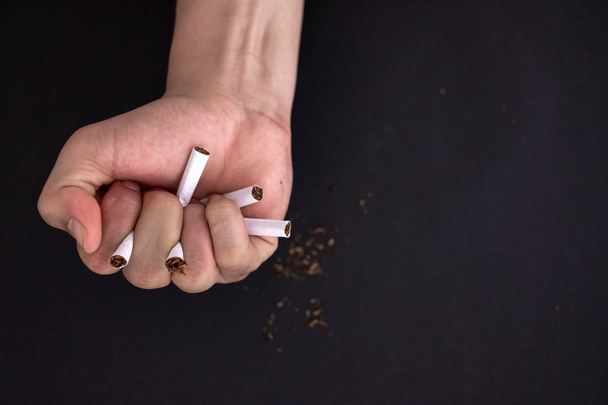 Rzucić palenie, ręka trzymać papierosa zniszczyć izolowane na czarnym ciemny - Zdjęcie, obraz