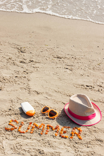 Wort Sommer, Sonnenbrille, Sonnencreme und Strohhut am Strand, Sommerzeit - Foto, Bild