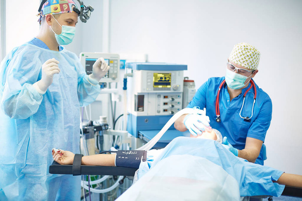 Mehrere Ärzte umgeben Patientin auf Operationstisch - Foto, Bild