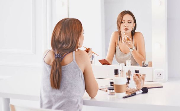 Amazing young woman doing her makeup in front of mirror. Portra - Photo, Image