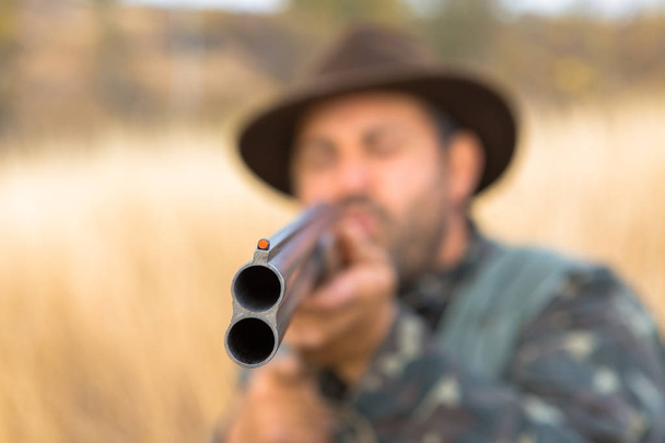 Caçador com um chapéu e uma arma em busca de presa na estepe, visa a presa
 - Foto, Imagem