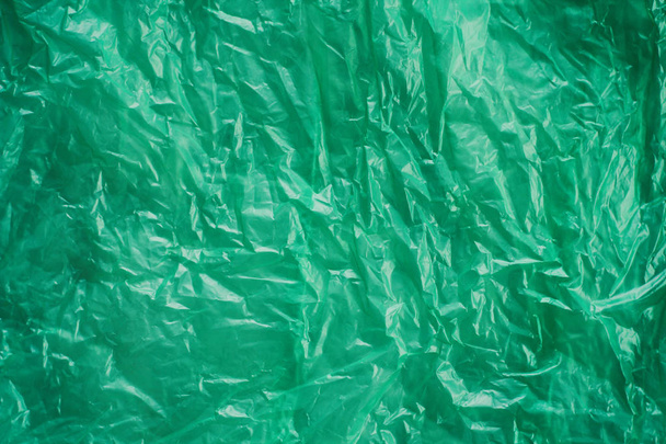 Green crumpled plastic bag texture background. Waste recycle concept. Polyethylene clear garbage bags.  - Foto, Imagen
