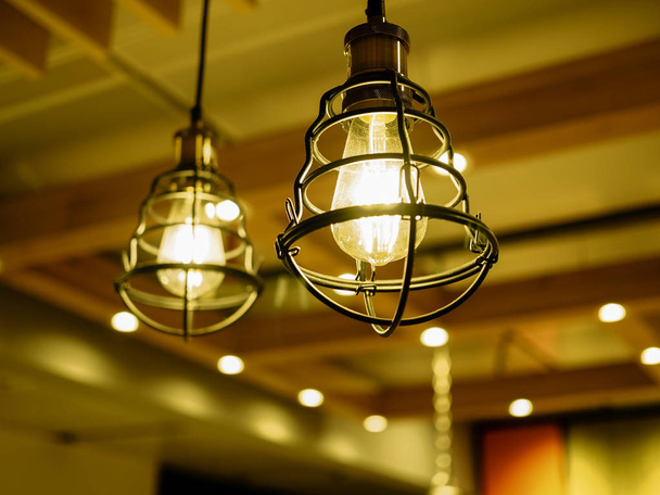 Nahaufnahme exponierter Glühbirnen in Metallkäfigen, die mit Sof glühen - Foto, Bild