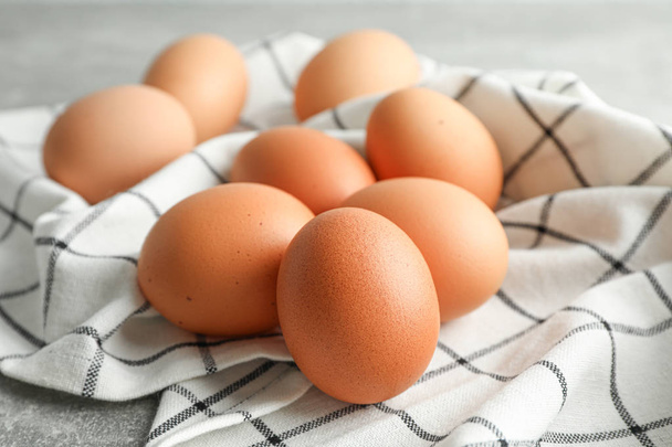Brown chicken eggs in kitchen towel on grey background, space fo - Photo, Image