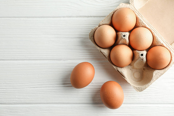 Brown chicken eggs in carton box on white background, space for  - Φωτογραφία, εικόνα
