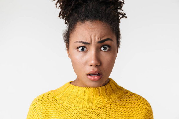 Beautiful young african confused woman posing isolated over white wall background. - 写真・画像