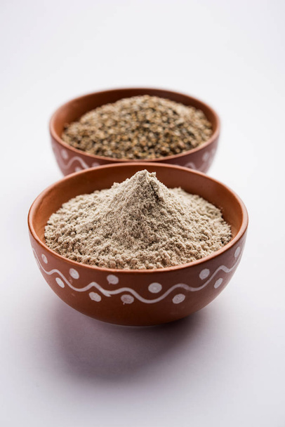 Bajra (mijo perla) / granos de sorgo con su harina o polvo en un bol, enfoque selectivo
 - Foto, Imagen