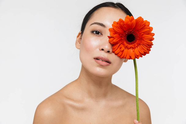 Beautiful young pretty asian woman with healthy skin posing naked isolated over white wall background holding flower. - Fotografie, Obrázek