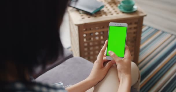 Student at home using smartphone with green mock-up screen swiping - Materiał filmowy, wideo
