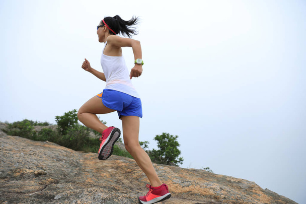 Joven mujer fitness corriendo hasta la cima de la montaña junto al mar
 - Foto, Imagen