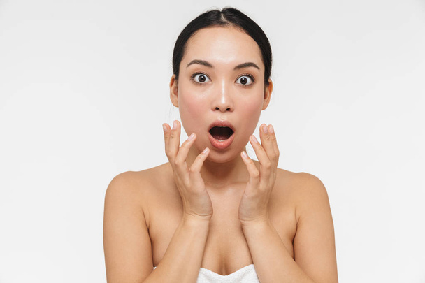 Beautiful shocked young pretty asian woman with healthy skin posing naked isolated over white wall background. - 写真・画像
