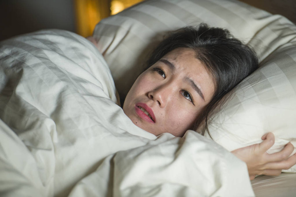 mladá spící dáma krásná a vystrašená Asijská Čínská žena ležela na posteli a probudila noční můru, když sledovala zombie filmový horor ve strachu a vystresované tváři  - Fotografie, Obrázek