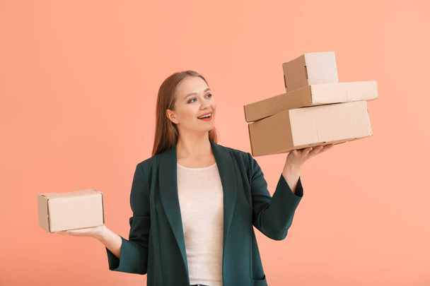 Young woman with cardboard boxes on color background - Foto, Imagen