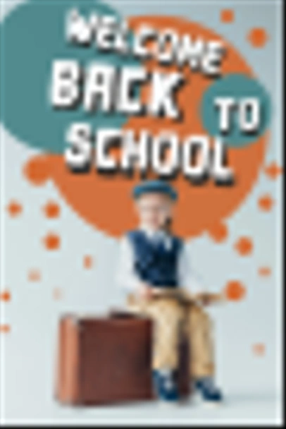 smiling kid in retro vest and cap sitting on suitcase and holding book on grey background with back to school illustration  - Photo, Image