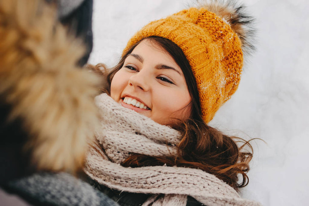 寒い季節の森の自然公園で幸せなカップル。黄色い帽子をかぶった幸せなブルネットの女の子。旅行冒険愛の物語 - 写真・画像