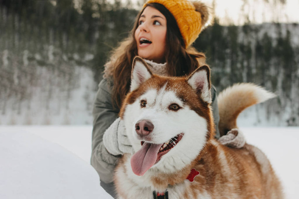 Red dog husky with his mistress brunette girl in forest outdoors in the cold season - Photo, Image