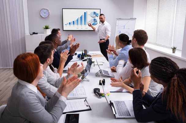 Group Of Multi Ethnic People Clapping For A Successful Businessman Giving Presentation On Screen - Photo, Image