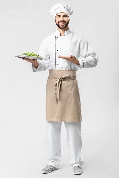 Jóképű férfi séf salátával, fehér alapon - Fotó, kép
