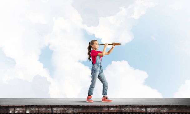 Cute kid girl standing on house roof and looking in spyglass - Φωτογραφία, εικόνα