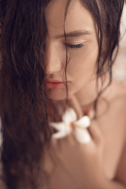 closeup wet woman portait with plumeria tropical flower in the h - Фото, изображение