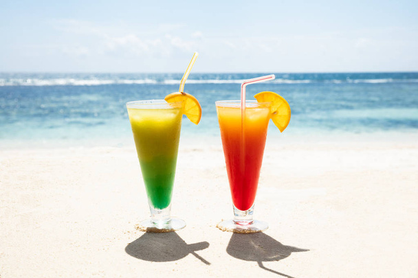 Two Glasses Of Colorful Cocktails On The Sandy Beach Against Blue Sky - Foto, afbeelding