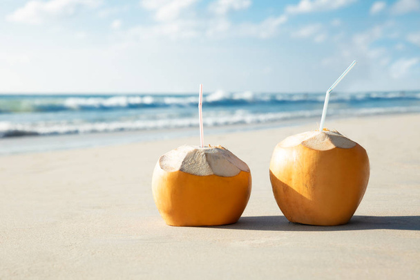 Close-up Of Two Coconuts With Drinking Straw On Sand At Beach - Valokuva, kuva