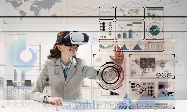 Horizontal shot of young successful business woman sitting inside office and using virtual reality headset with digital media interface - Foto, imagen