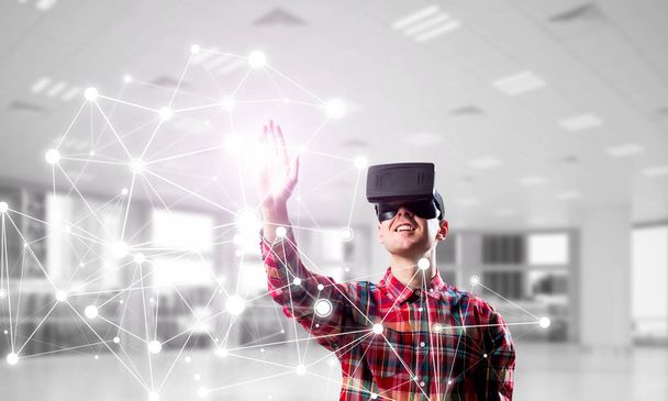 Young man with virtual reality headset or 3d glasses over connection background. Mixed media - Fotoğraf, Görsel
