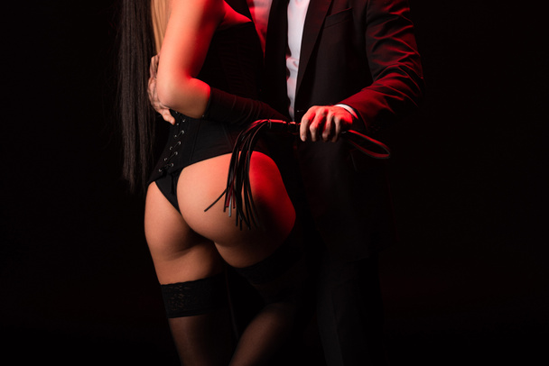 partial view of bdsm couple with flogging whip isolated on black - Photo, Image