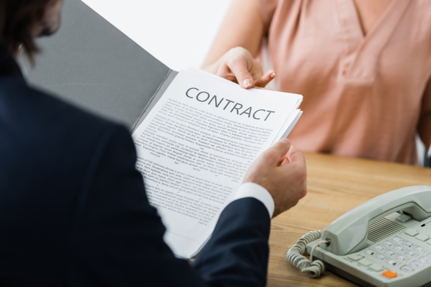 cropped view of woman and businessman holding contract in hands - Foto, imagen