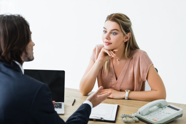 selective focus of beautiful woman looking at businessman and sitting in office - Photo, image