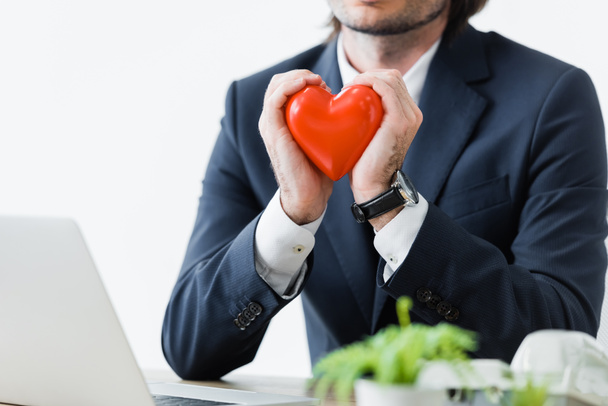 обрезанный взгляд бизнесмена, держащего в руках красное сердце, изолированное по белому, концепции медицинского страхования
 - Фото, изображение