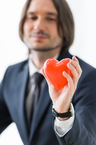 επιλεκτική εστίαση του επιχειρηματία που κρατά την κόκκινη καρδιά σε χέρια απομονωμένα σε λευκό, ιατρική ασφαλιστική έννοια - Φωτογραφία, εικόνα