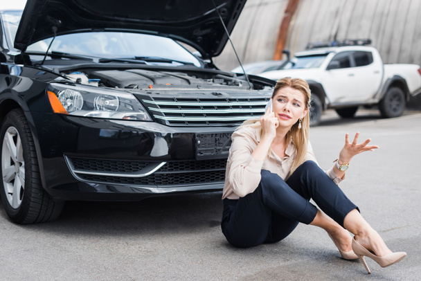 sad businesswoman talking on smartphone and sitting near broken auto, car insurance concept car insurance concept - Фото, зображення