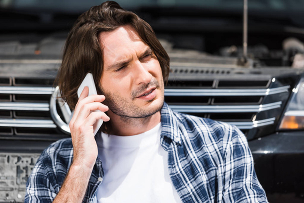 hombre molesto en ropa casual hablando en el teléfono inteligente cerca de auto roto, concepto de seguro de coche
 - Foto, Imagen