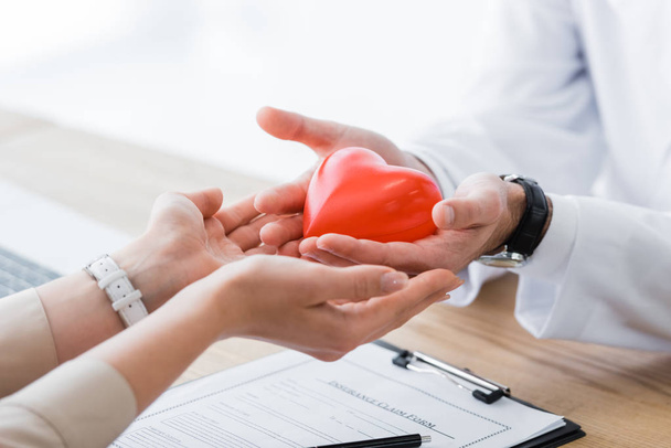przycięte widzenia lekarza i pacjenta trzymając czerwone serce w rękach, koncepcja ubezpieczenia medycznego - Zdjęcie, obraz