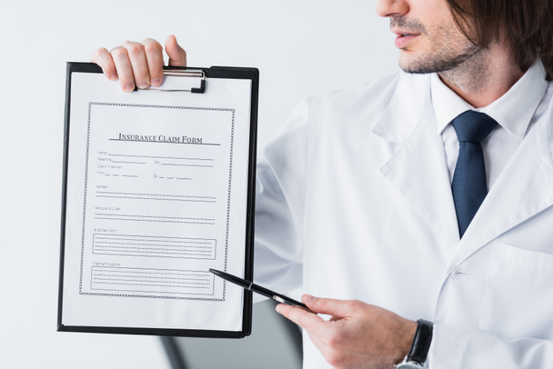 vue recadrée du médecin en manteau blanc pointant avec stylo sur le document médical
  - Photo, image