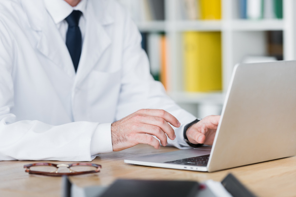 cropped view of doctor in white coat working with laptop - Foto, imagen