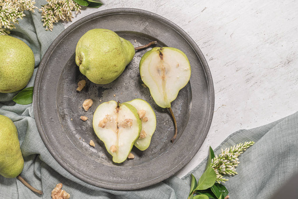 Tasty pears with nuts. A table decorated with flowers and a plate of pears cut into the plate. - Fotografie, Obrázek