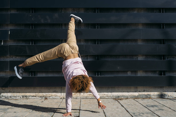 Young woman breakdancer, breakdance performance upside down motion on the street. - Zdjęcie, obraz