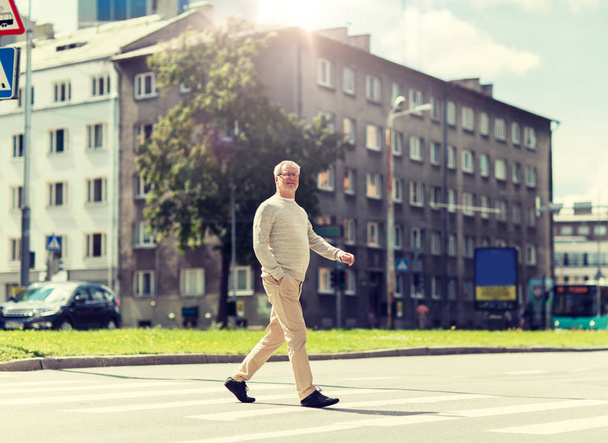 Senior man lopen langs stad zebrapad - Foto, afbeelding